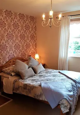 a bedroom with a bed with a chandelier and a window at The Pelican Guesthouse in Ashwellthorpe
