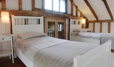 a bedroom with two white beds and a window at Partridge Lodge Self Catering houses in Woodbridge