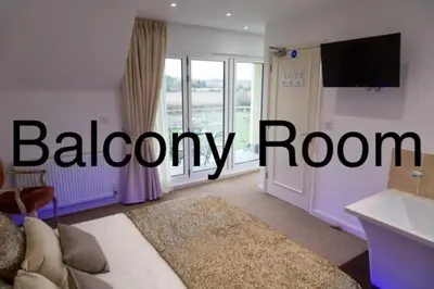 a living room with a bed and a balcony room at Elmcroft Guest House in Epping
