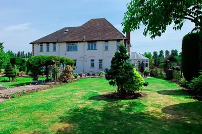 a large white house with a tree in the yard at Elmcroft Guest House in Epping