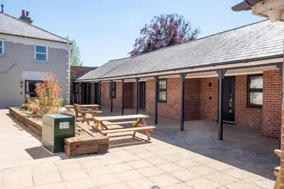 a patio with two wooden benches in front of a building at Birch - Three Tuns Apartments - Pettistree, Wickham Market - by Aldeburgh Coastal Cottages in Pettistree