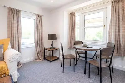 a living room with a table and chairs and a window at Elm - Three Tuns Apartments, Pettistree, Wickham Market - by Aldeburgh Coastal Cottages in Pettistree