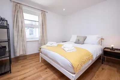 a bedroom with a bed with a yellow blanket on it at Weeping Willow - Three Tuns Apartments, Pettistree, Wickham Market - by Aldeburgh Coastal Cottages in Pettistree