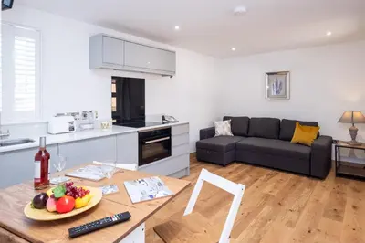 a kitchen and living room with a table and a couch at Weeping Willow - Three Tuns Apartments, Pettistree, Wickham Market - by Aldeburgh Coastal Cottages in Pettistree