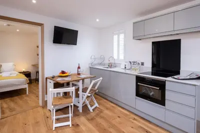 a kitchen and dining room with a table and a bed at Weeping Willow - Three Tuns Apartments, Pettistree, Wickham Market - by Aldeburgh Coastal Cottages in Pettistree