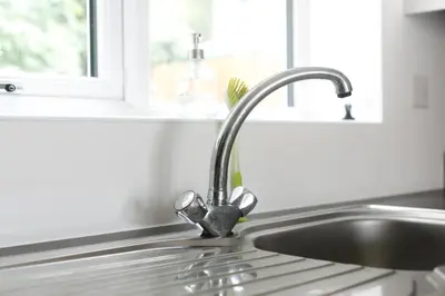 a kitchen sink with a faucet next to a window at Hertford Serviced Apartments in Hertford