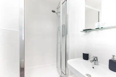 a white bathroom with a shower and a sink at Hertford Serviced Apartments in Hertford