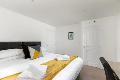 a white bedroom with a bed with white sheets and pillows at Hertford Serviced Apartments in Hertford