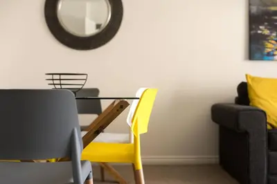a dining room table with yellow chairs and a mirror at Hertford Serviced Apartments in Hertford