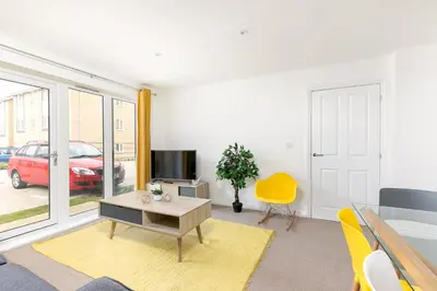 a living room with a table and a tv at Hertford Serviced Apartments in Hertford