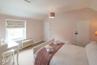 a bedroom with a bed and a desk and a window at Little Tern Cottage in Aldeburgh
