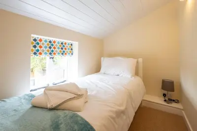 a bedroom with a white bed and a window at Little Tern Cottage in Aldeburgh