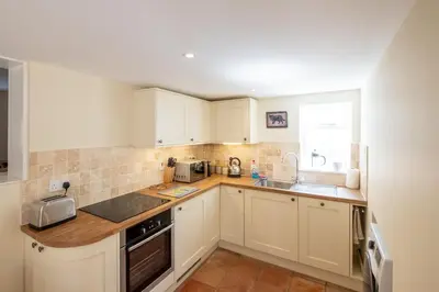 a kitchen with white cabinets and a sink at Little Tern Cottage in Aldeburgh