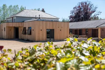 a barn with a building in the background at Rowan - Three Tuns Apartments , Wickham Market - by Aldeburgh Coastal Cottages in Pettistree