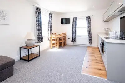 a kitchen and living room with a couch and a table at Rowan - Three Tuns Apartments , Wickham Market - by Aldeburgh Coastal Cottages in Pettistree