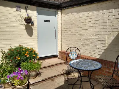 a patio with a table and chairs in front of a door at The Annexe in Hawkedon