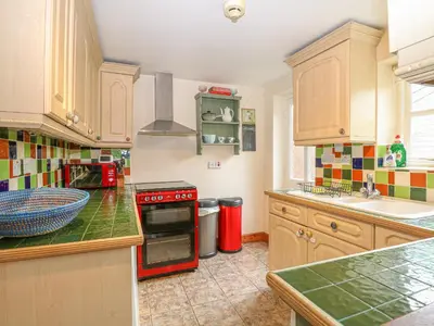 a kitchen with wooden cabinets and a red stove top oven at 3 Station Cottages in Wymondham
