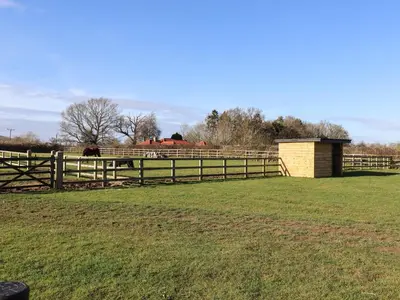 a fence in a field with a horse in the background at Grange Barn in Hessett