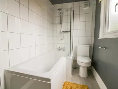 a white bathroom with a tub and a toilet at 2 Hillside Cottages in Ipswich