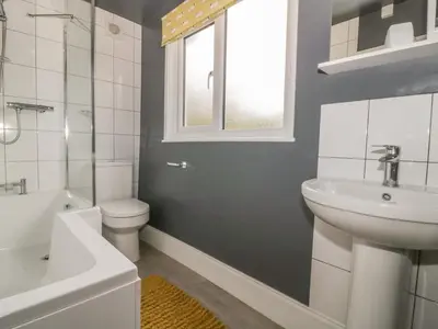 a bathroom with a sink and a toilet and a window at 2 Hillside Cottages in Ipswich