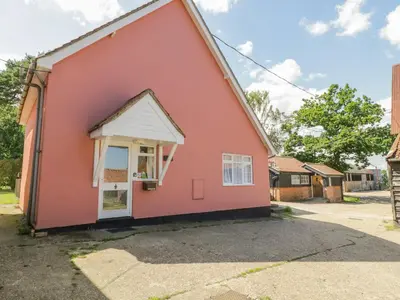 a red house with a white window in a driveway at The Bothy in Eye