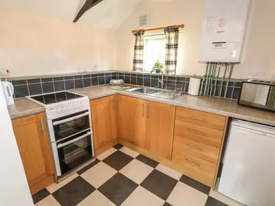 a kitchen with wooden cabinets and a checkered floor at The Bull Pen in Eye