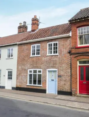 a brick house with red doors on a street at A quaint Wymondham cottage in Norwich