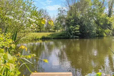 a view of a river with a wooden dock at 16th Century Cartlodge with private hot tub in Diss