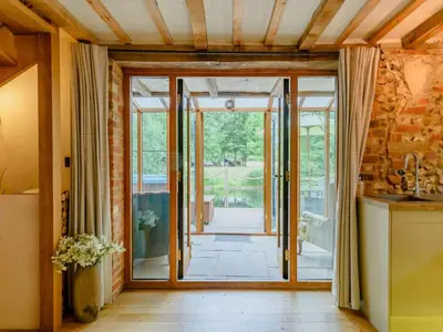 a kitchen with glass doors leading to a patio at 16th Century Cartlodge with private hot tub in Diss