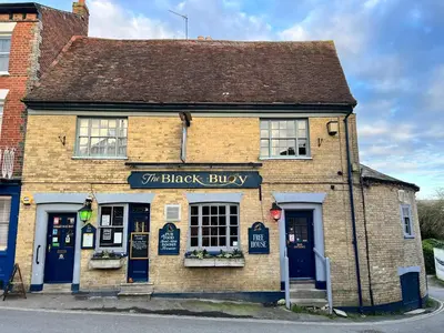 a brick building with blue doors and windows at Black Buoy Inn in Wivenhoe