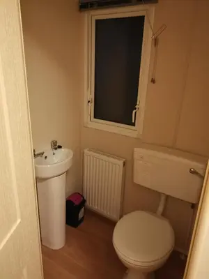 a bathroom with a toilet and a sink and a window at Caledonian Caravan in Jaywick Sands