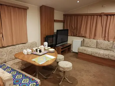 a living room with a table and a couch and a tv at Caledonian Caravan in Jaywick Sands