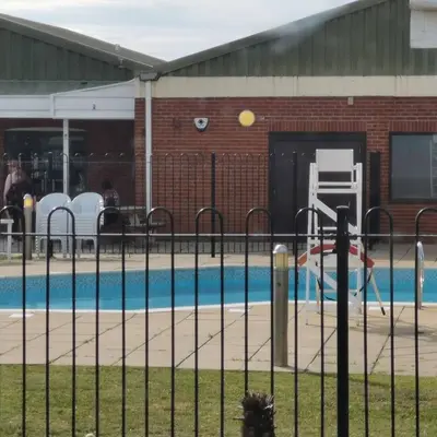 a swimming pool with a fence next to it at Caledonian Caravan in Jaywick Sands