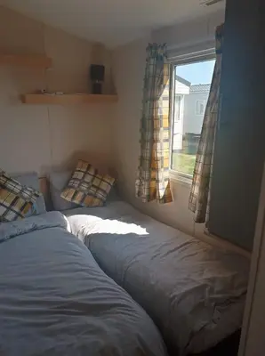 two beds in a small room with a window at Caledonian Caravan in Jaywick Sands