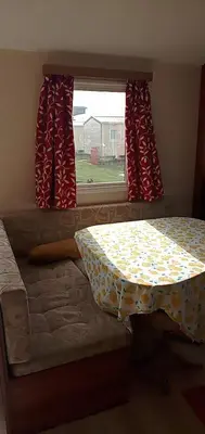 a bedroom with a bed and a window with red curtains at Caledonian Caravan in Jaywick Sands