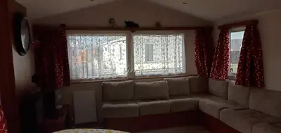 a living room with a couch and two windows at Caledonian Caravan in Jaywick Sands