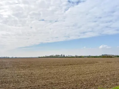 an empty field with a cloudy sky in the background at Hill Farm Cottage in Stretham