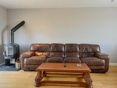 a brown leather couch in a living room with a coffee table at Hill Farm Cottage in Stretham