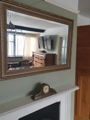 a mirror over a fireplace with a clock on a mantle at Harry's bed and breakfast in Cambridge