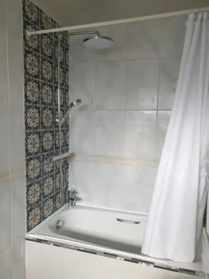a shower with a white shower curtain in a bathroom at Harry's bed and breakfast in Cambridge