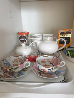a shelf with three cups and saucers in a refrigerator at Harry's bed and breakfast in Cambridge