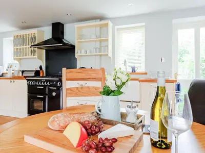 a table with a bottle of wine and a plate of food at Coachman's Cottage - Uk11449 in Mellis