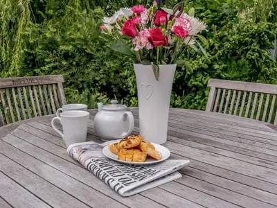 a table with a plate of pastries and a vase with flowers at Coachman's Cottage - Uk11449 in Mellis