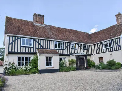 a large black and white house with a driveway at Coachman's Cottage - Uk11449 in Mellis