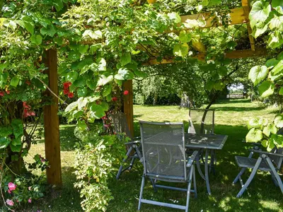 a table and chairs under a pergola in a garden at Coachman's Cottage - Uk11449 in Mellis