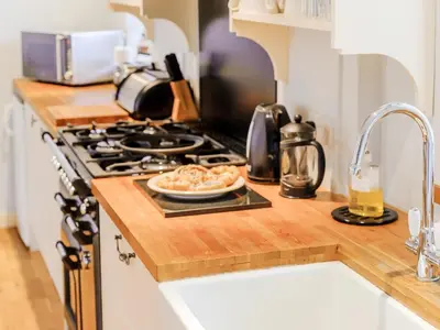 a kitchen counter with a plate of food on a stove at Coachman's Cottage - Uk11449 in Mellis