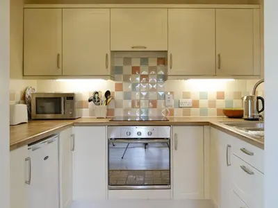 a white kitchen with white cabinets and a stove at The Studio-Uk11822 in Westleton