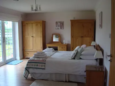 a bedroom with a large bed with wooden cabinets at Spring Paddocks B&B in Furneux Pelham