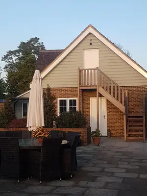 a house with a table and an umbrella in front of it at Spring Paddocks B&B in Furneux Pelham