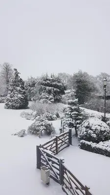a park covered in snow with a fence and benches at Spring Paddocks B&B in Furneux Pelham